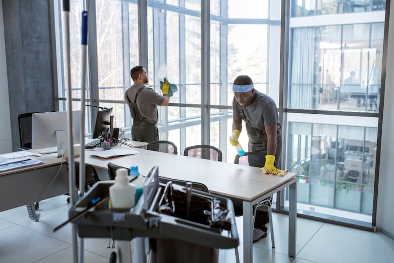 Sauberes büro motiviert mitarbeiter. Reinigunsmitarbeiter saubern ein büro mit geeigneten reinigungsmittel.